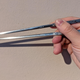 hand holding a pair of chopsticks